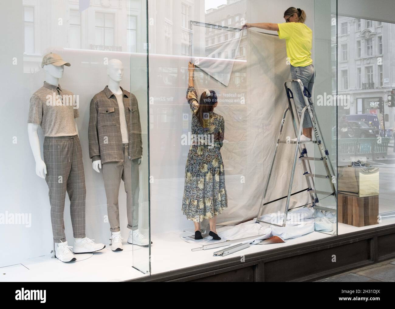 Window dressers prepare a shop window following the introduction of