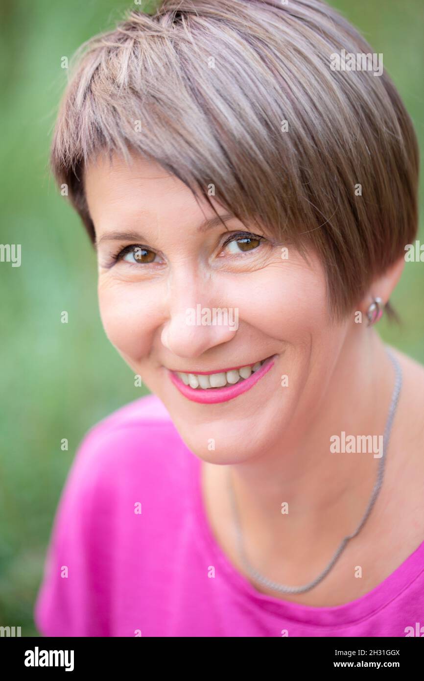 Portrait of a fifty-year-old woman. A middle-aged woman is looking at the camera and smiling. Stock Photo