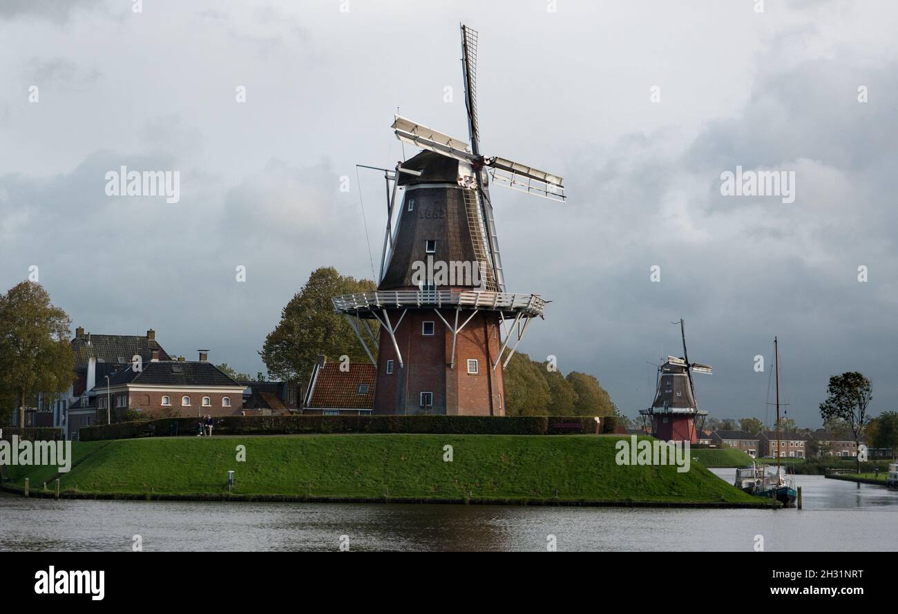 Two windmills on the bulwark of the old city Dokkum in the Netherlands on a dark and drizzly day in autumn Stock Photo