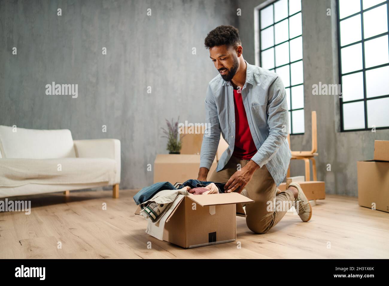 Happy young man putting clothes into packing boxes, moving home. New living concept Stock Photo