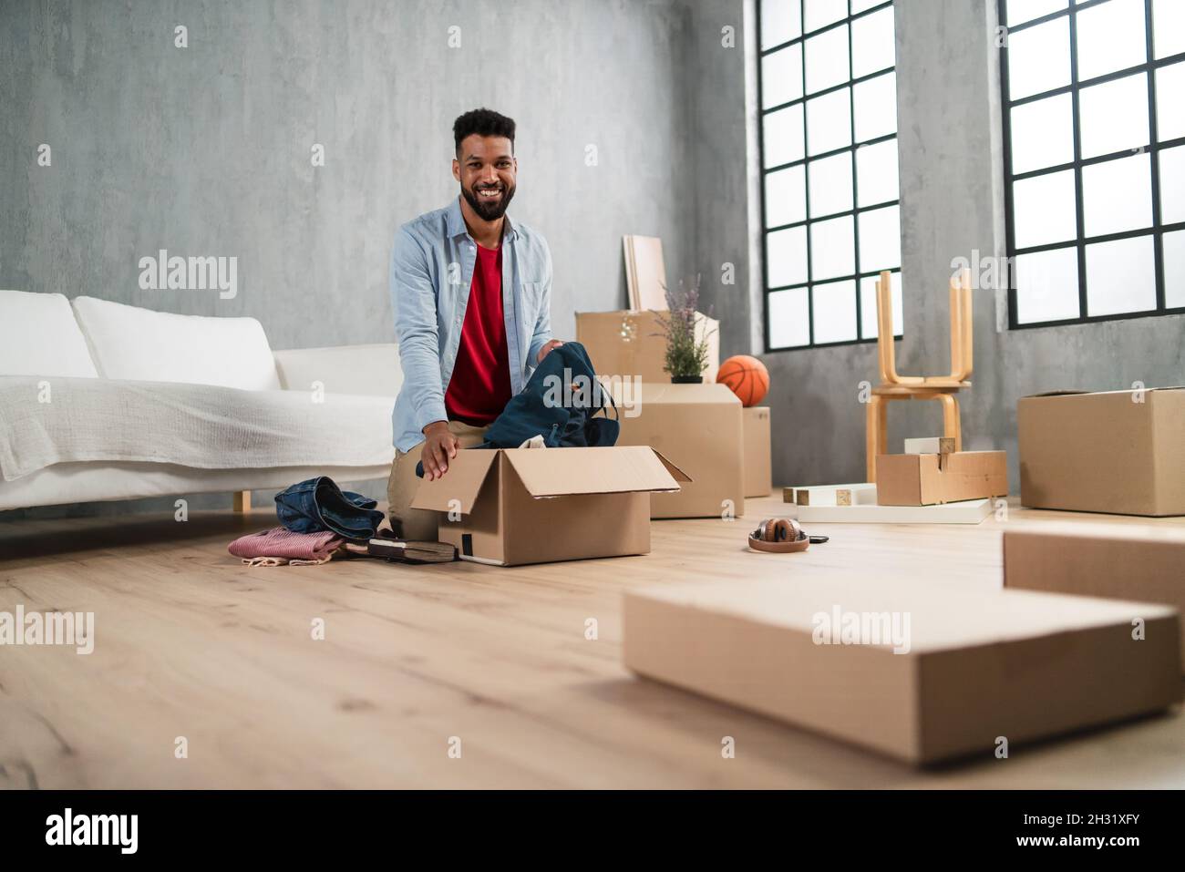 Happy young man putting clothes into packing boxes, moving home. new living concept Stock Photo