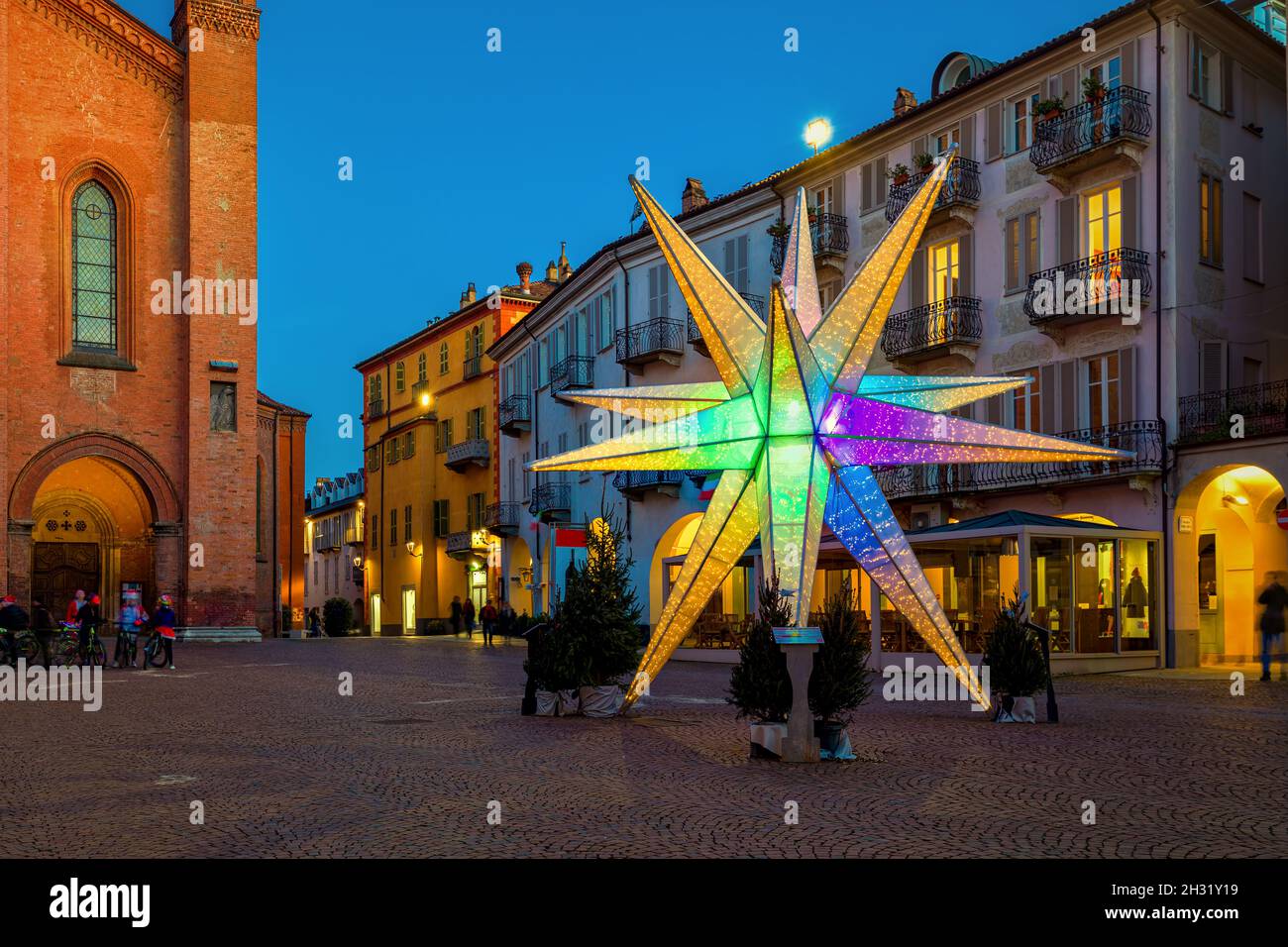 Illuminated colorful Christmas star on old town square in Alba, Piedmont, Northern Italy. Stock Photo