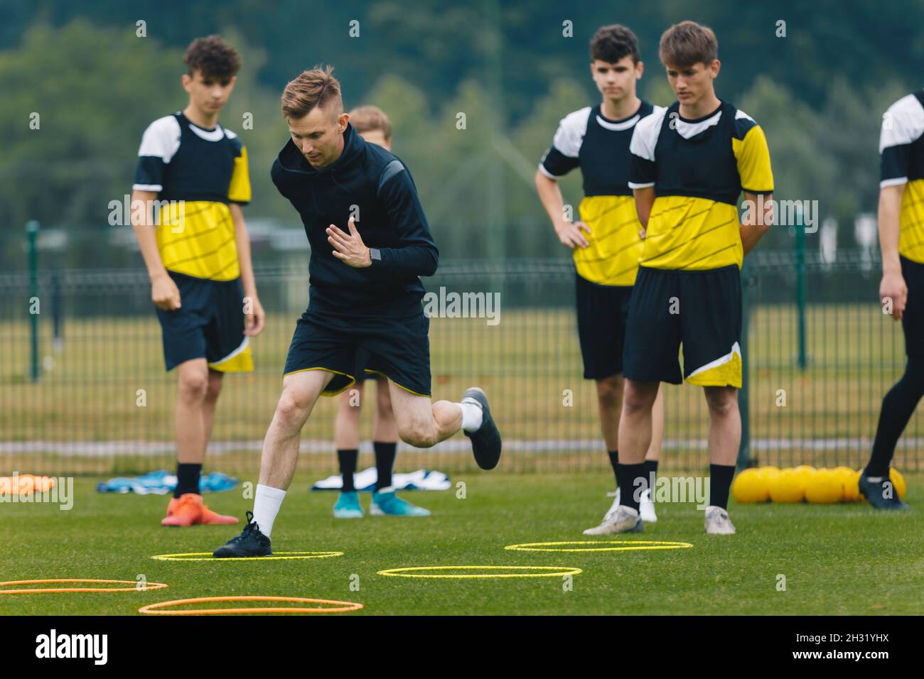 Young Football Coach on Training Session With Junior Footballers. Athletes Exercising With a Coach. Personal Trainer in Soccer Club Showing to Youth P Stock Photo