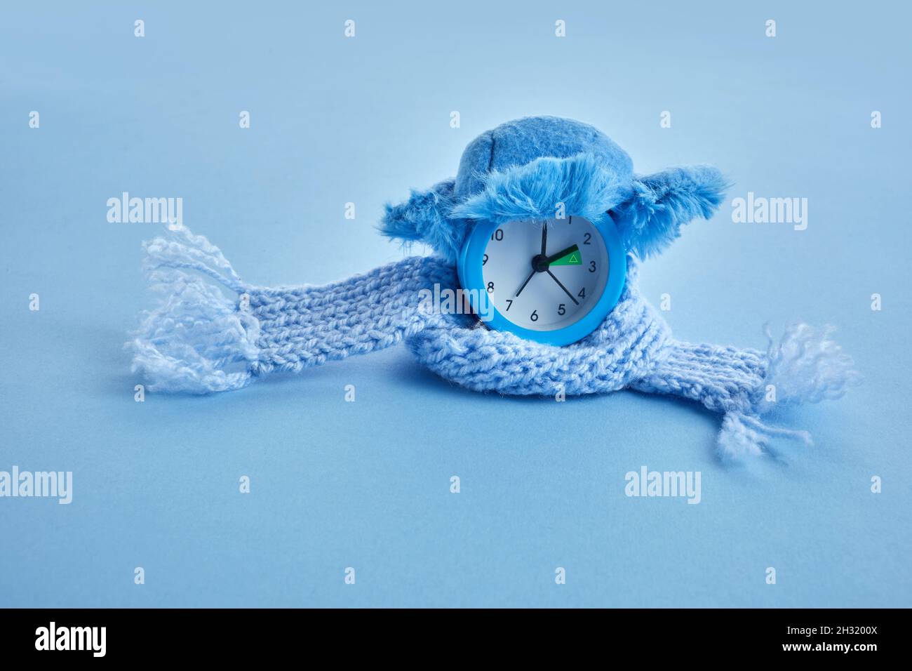 Clock changing from summer to winter time. Alarm clock with winter hat