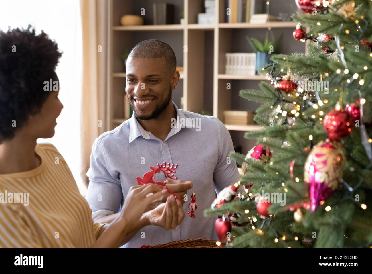 Happy african american couple decorating Christmas tree. Stock Photo