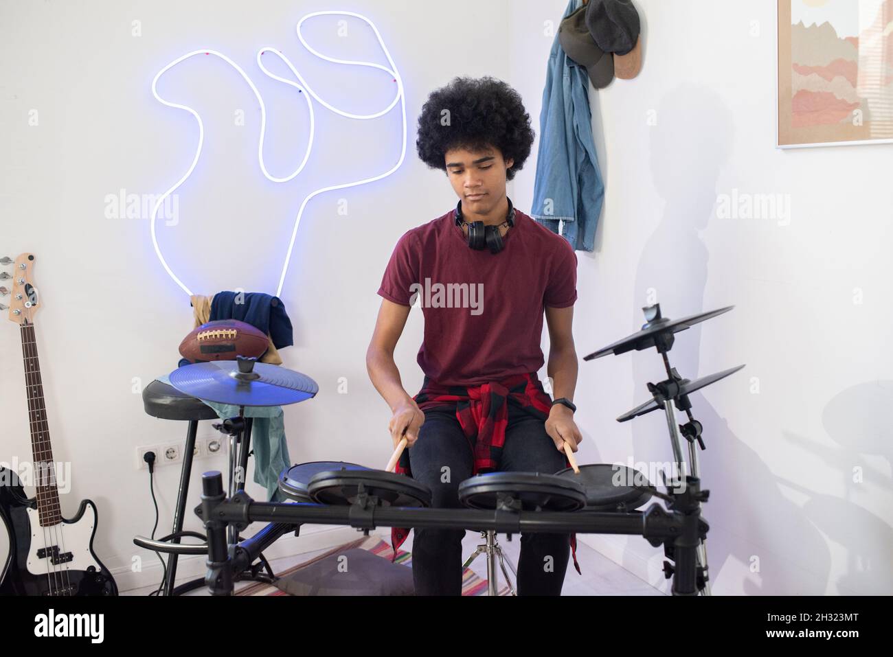 Teenage boy in casualwear sitting by drumset and beating on of drums during home repetition Stock Photo