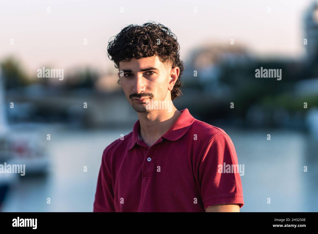 Young man with moustache and modern hair cut next to a river Stock Photo