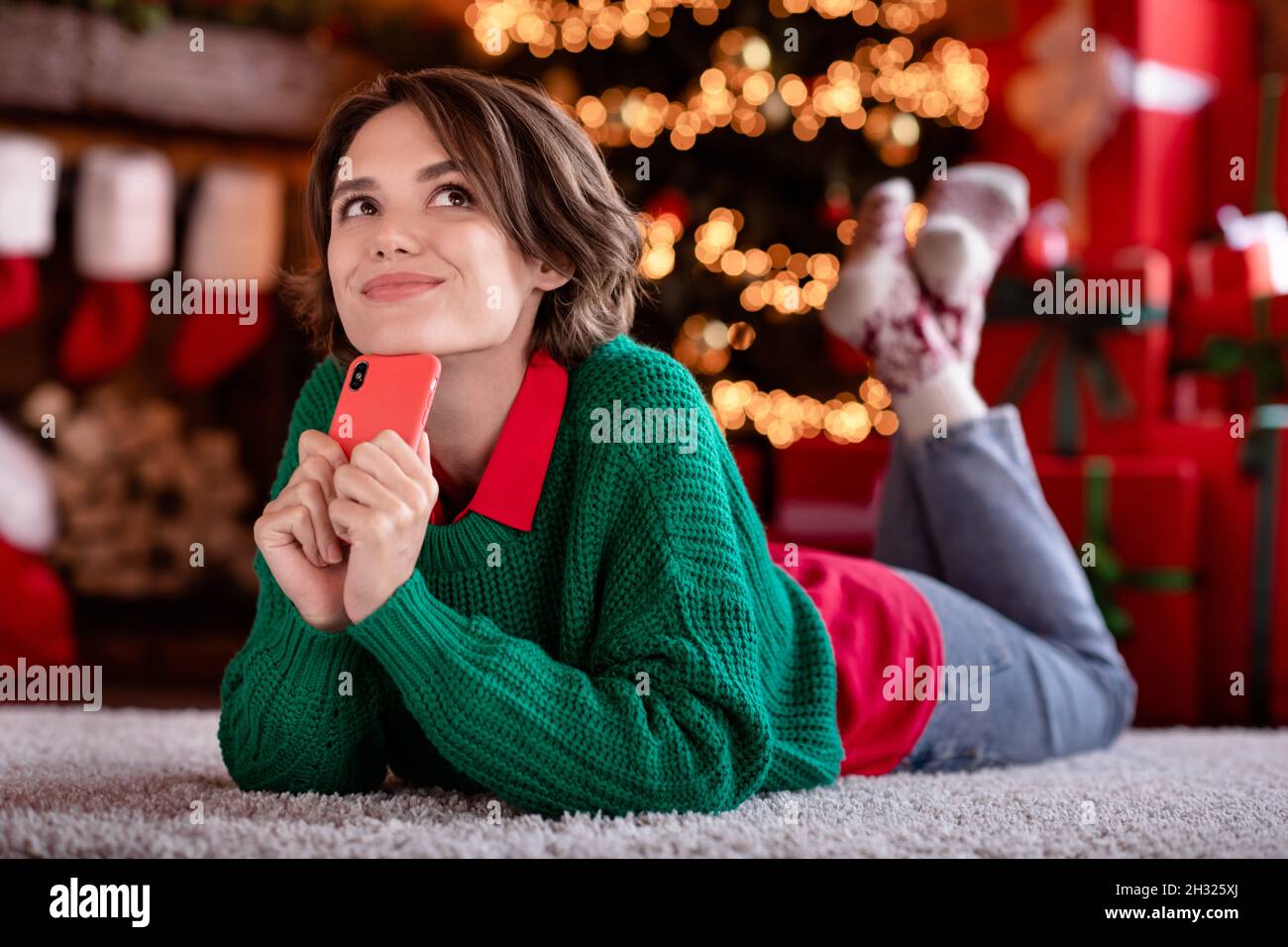 Full length photo of dream lady hold telephone wear green sweater jeans socks at evening in modern flat Stock Photo