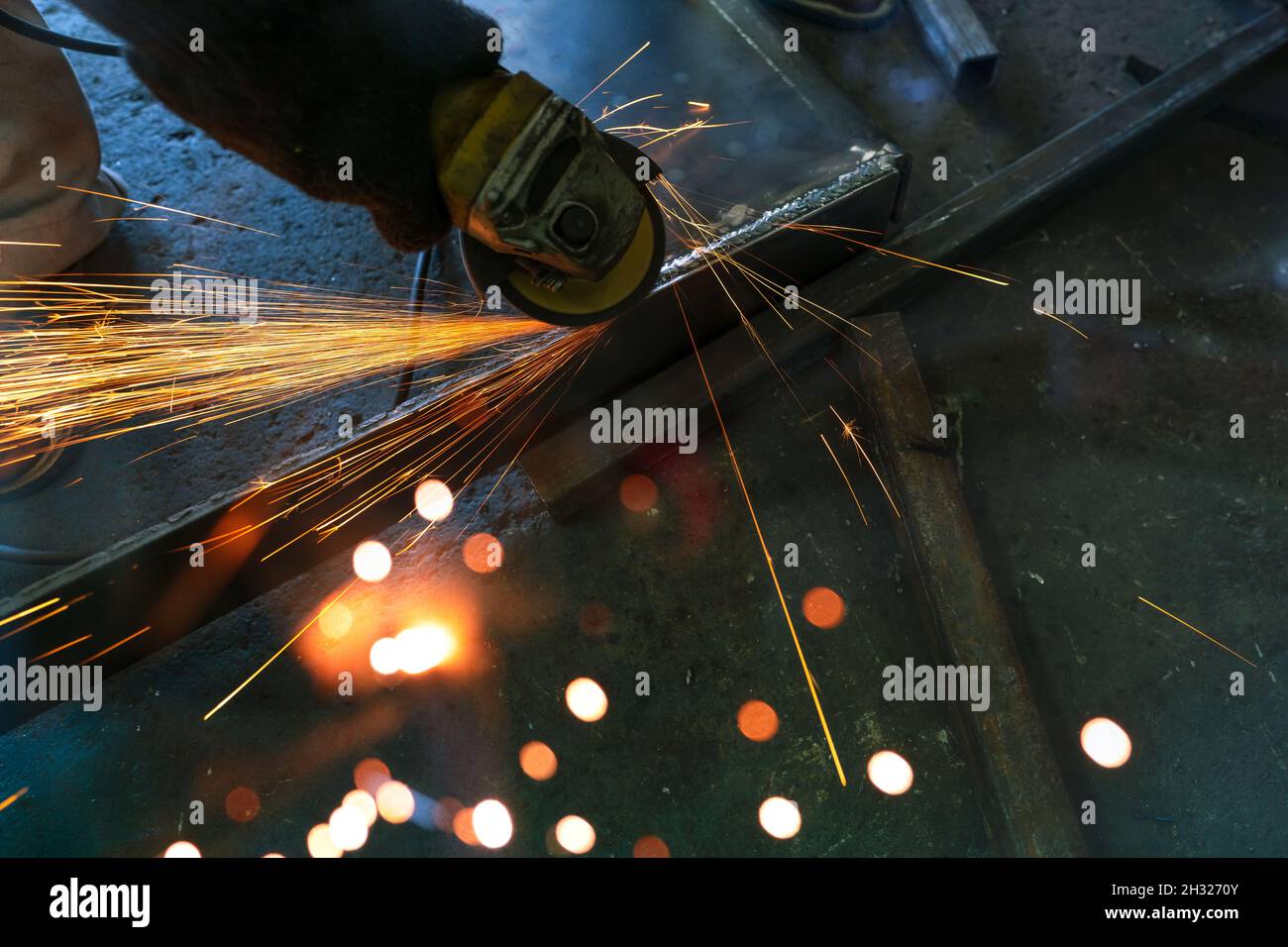 Industrial worker using angle grinder grinding metal on welding seams