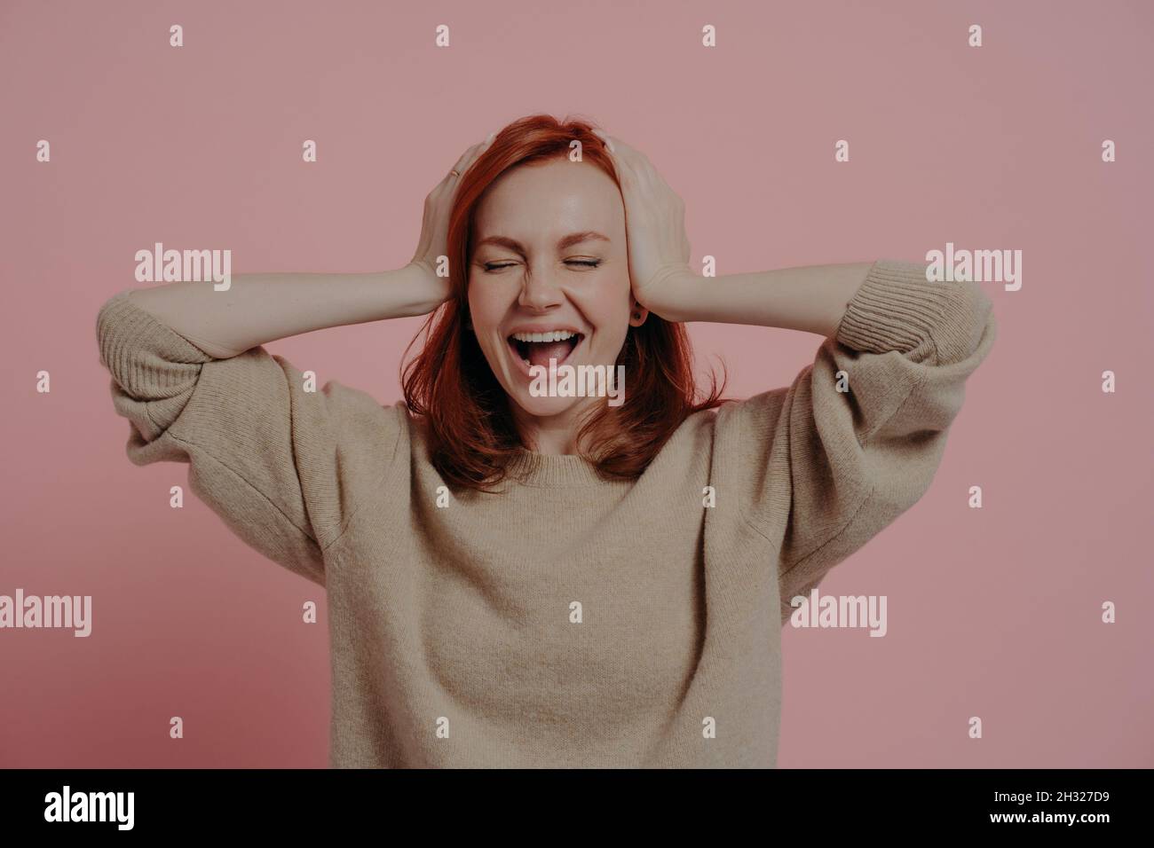 Excited caucasian red-haired woman reacting positively on good news isolated over pink background Stock Photo