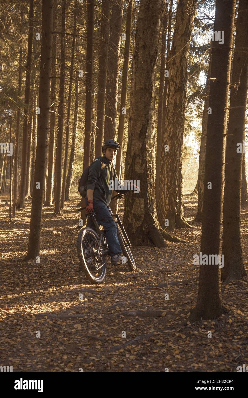 Russia, Moscow region, October 2021, A young man in a helmet on a sports bike in the forest, illuminated by sunlight. Stock Photo