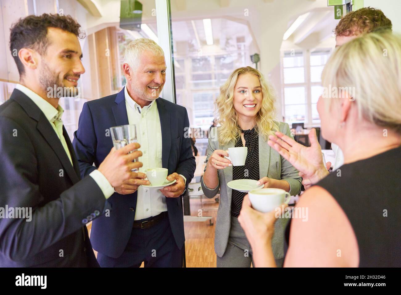 Group of business people having relaxed small talk with the boss during a coffee break Stock Photo