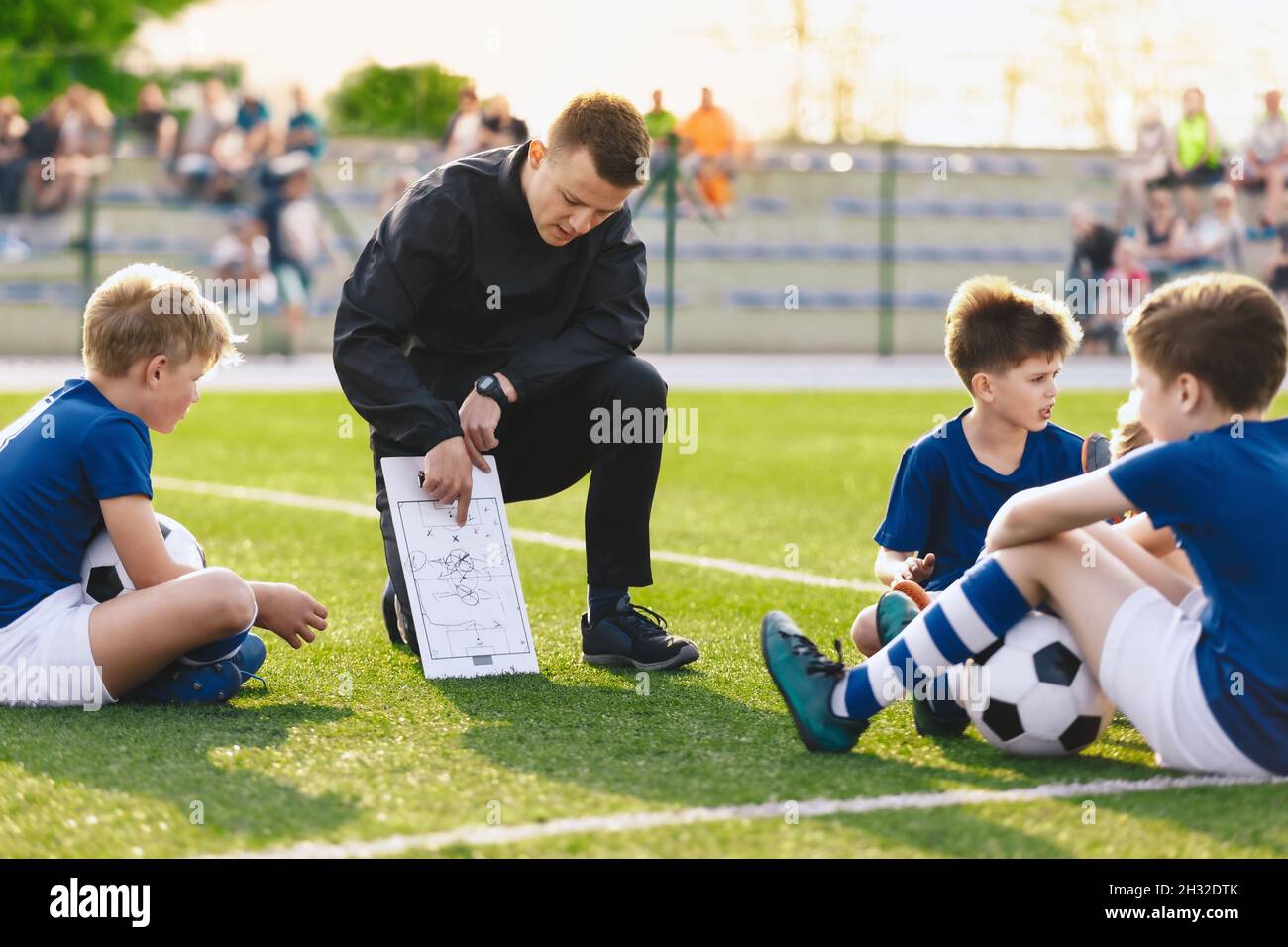 young-coach-teaching-children-boys-on-the-football-field-soccer