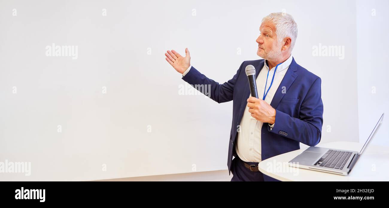 Elderly business man as a speaker with microphone at a presentation in the lecture hall Stock
