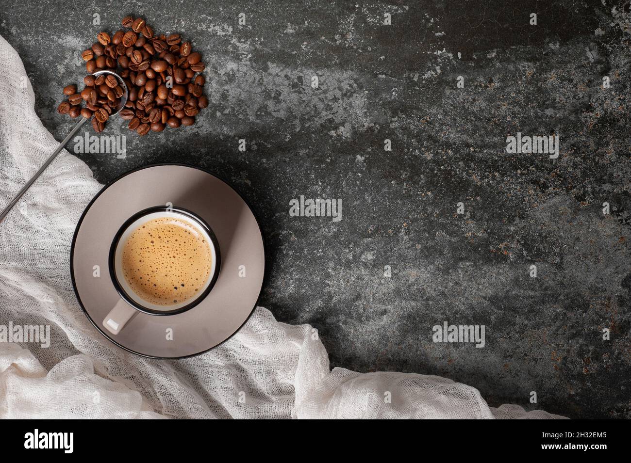a cup of coffee with beautiful foam near coffee beans are scattered on a concrete background top view copy space Stock Photo