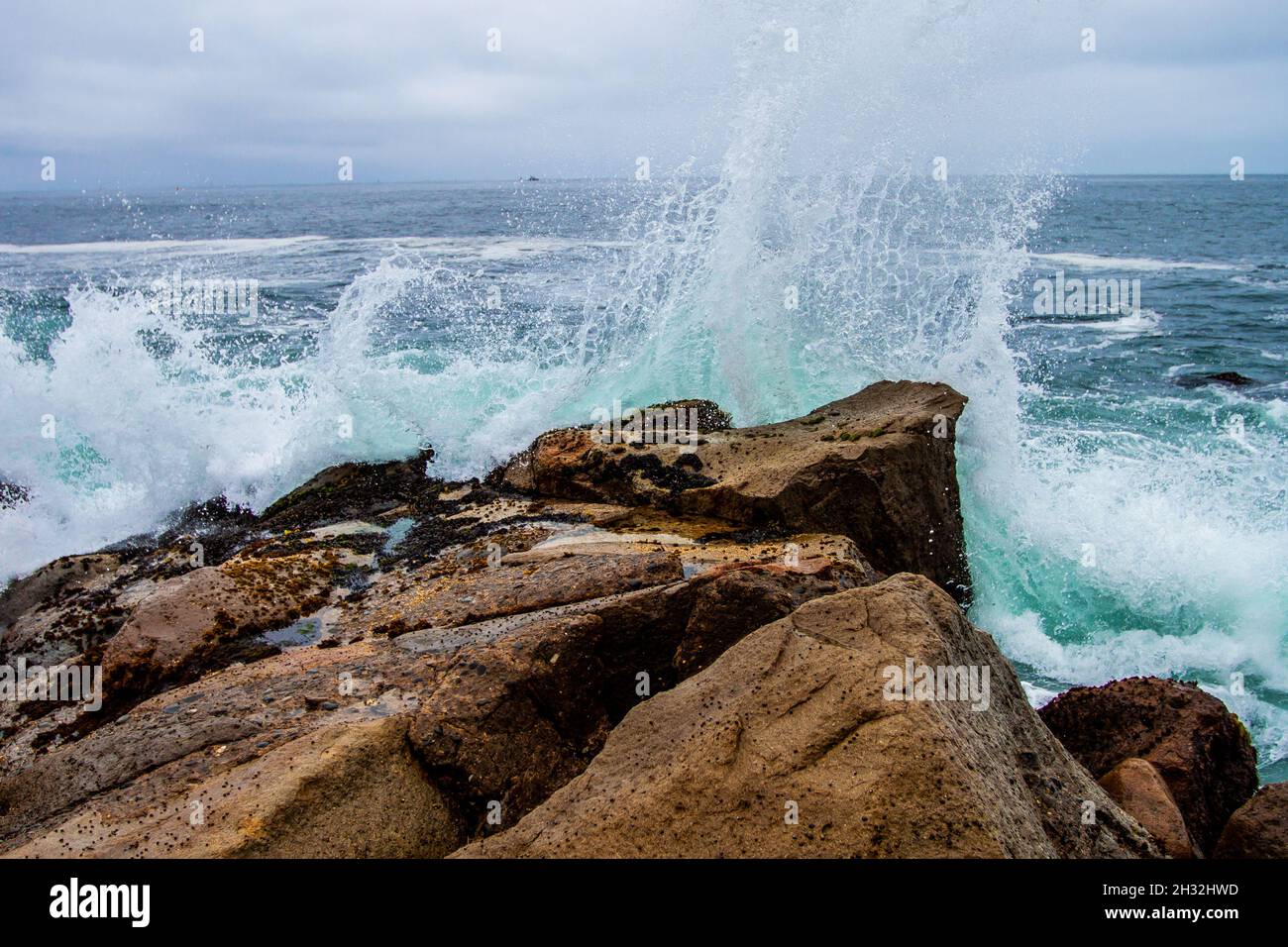 Wave Splashing Against Stones On Shore Close Up Water Crashing On The Wave Splashing Against Stones On Shore Close Up Water Crashing On The Rocky Shore Water Splash Stunning View Clear Cyan Blue Water 2H32HWD