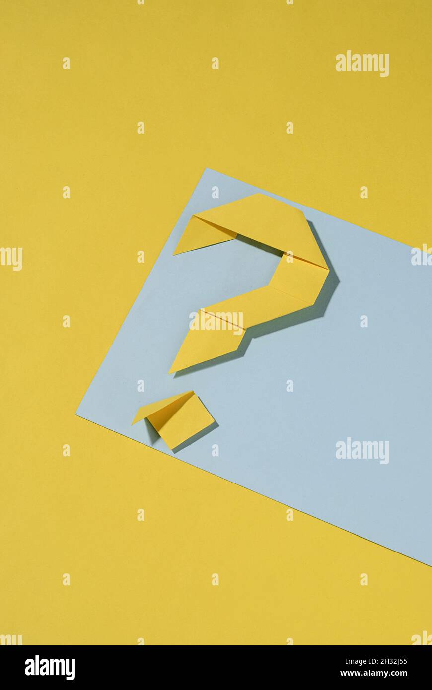 Yellow folded paper origami question mark on a blue banner over a