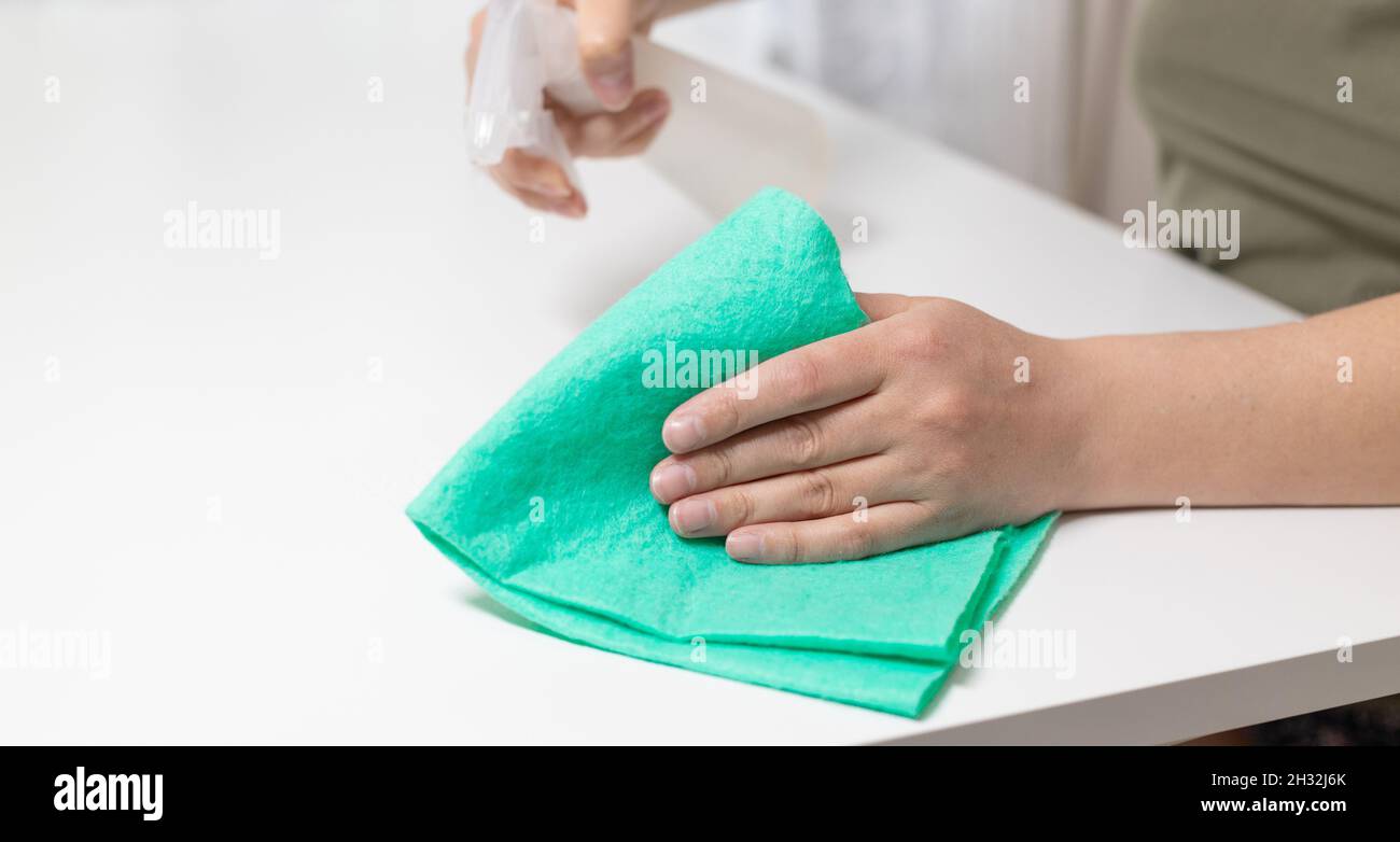 Young woman housekeeper is cleaning, wiping down table surface with ...
