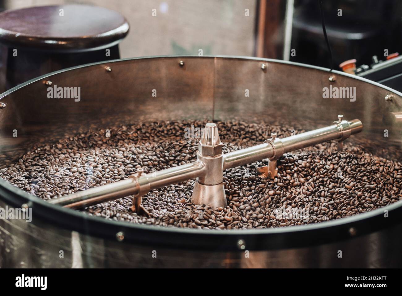 Roasting process of fresh coffee beans at factory. Metal drum full of coffee beans Stock Photo