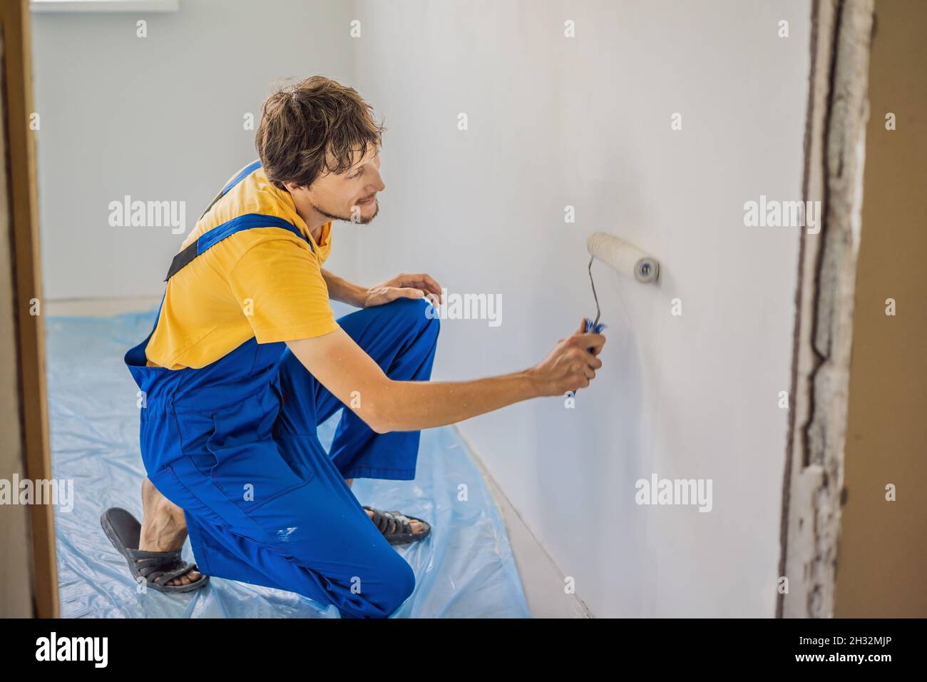 Professional painter worker painting and priming wall with painting