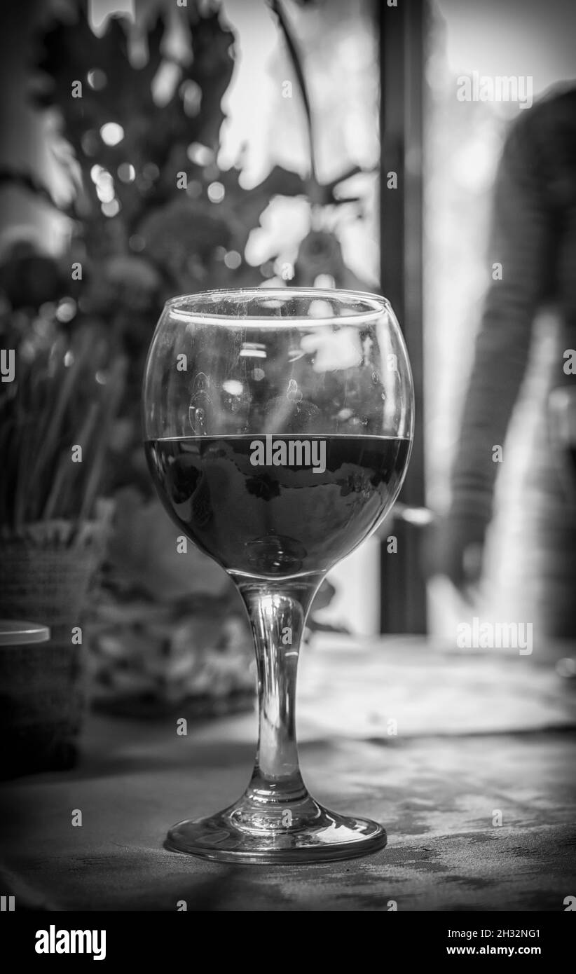 A glass of red wine in a home setting in black and white Stock Photo