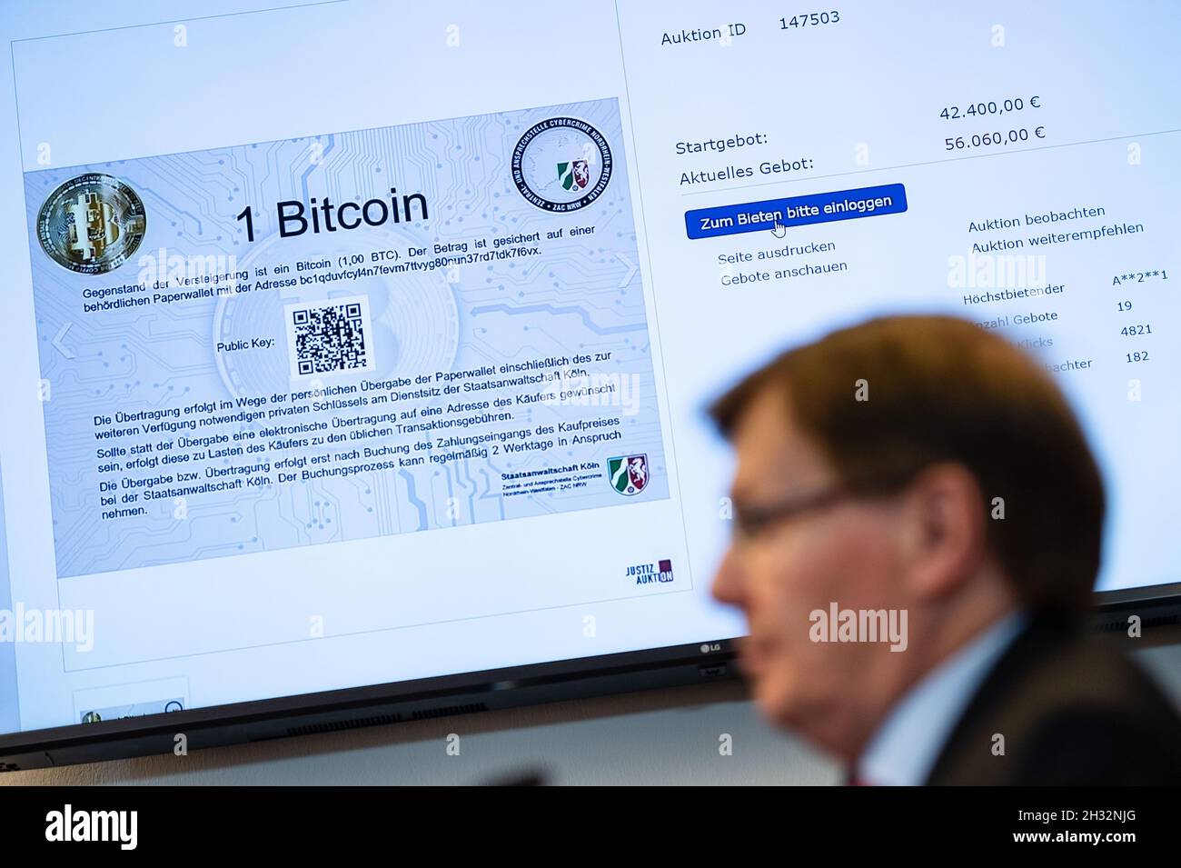 Cologne, Germany. 25th Oct, 2021. On a screen, the auction of a Bitcoin can be seen on the auction portal 'Justiz-Auktion'. In front of it sits North Rhine-Westphalia's Justice Minister Peter Biesenbach (CDU). The North Rhine-Westphalian justice system has started auctioning off seized Bitcoin for the first time. Credit: Marius Becker/dpa/Alamy Live News Stock Photo