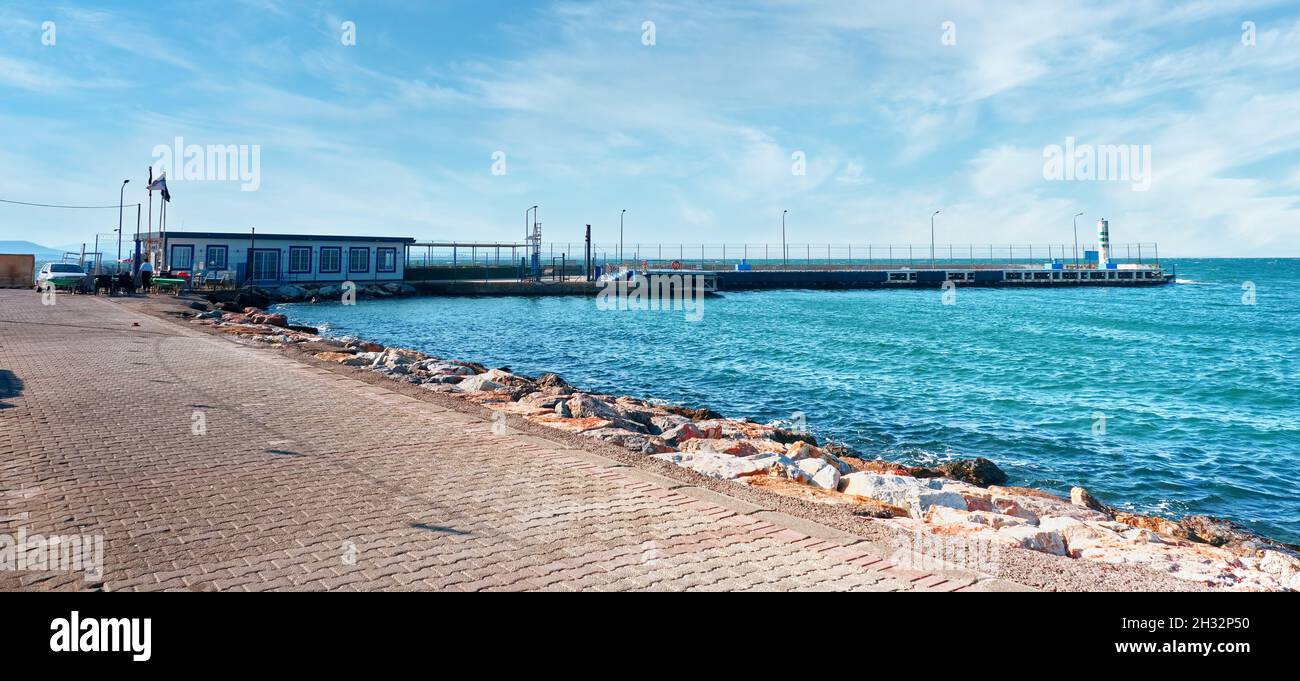 Urla, Turkey - September, 2021: Ferry port or pier and the lighthouse in Guzelbahce district in Urla, Izmir, Turkey. Stock Photo