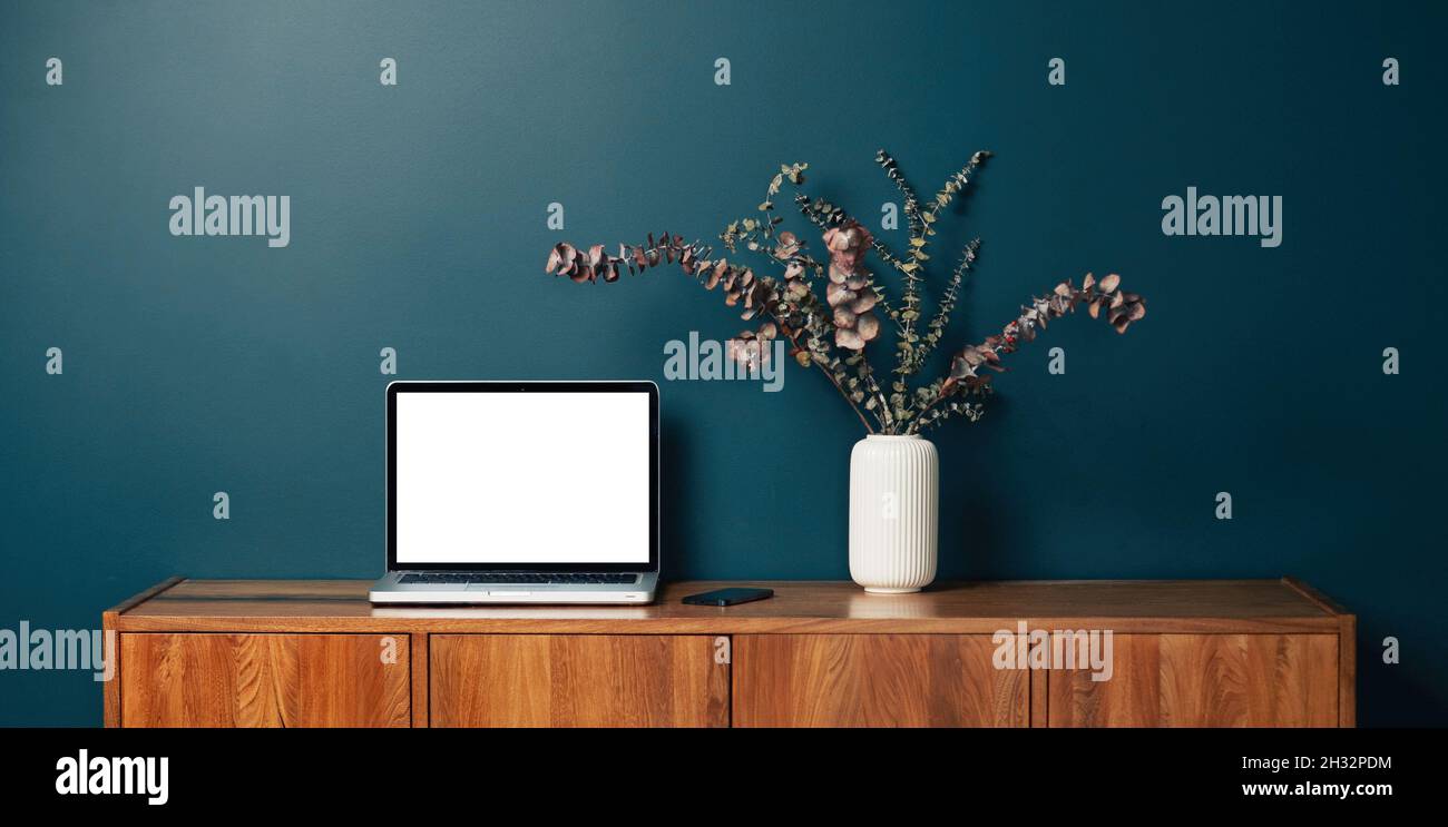 Laptop computer with empty blank mockup screen over emerald modern living room design. Home office, workplace, working or studying from home, distance Stock Photo