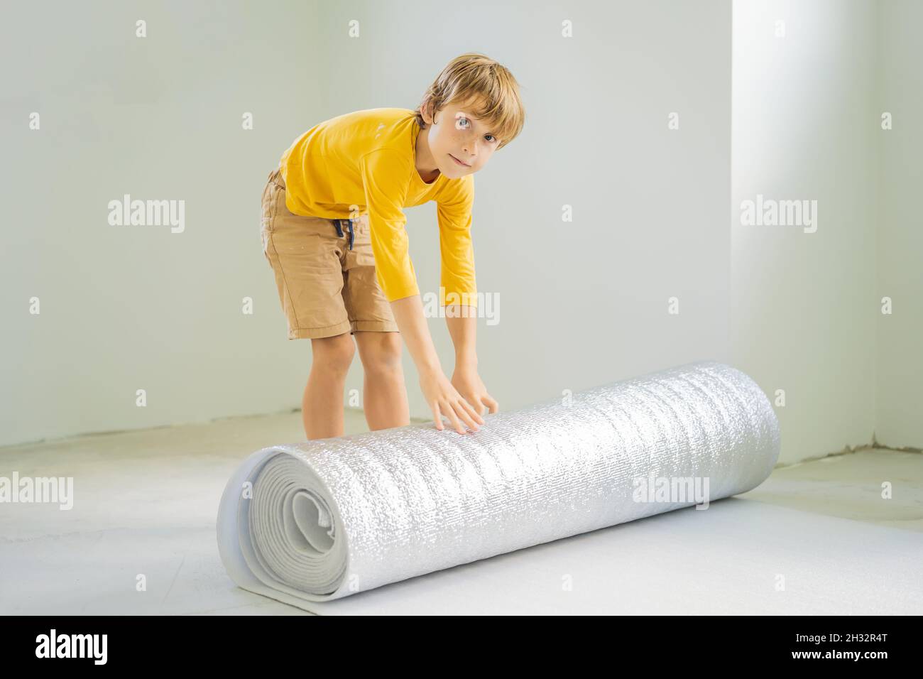 Boy are laying floor insulation. Roll of insulating cloth to install a
