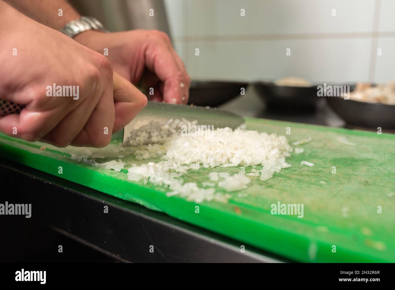 Chef cutting onion on a green cutting board Stock Photo