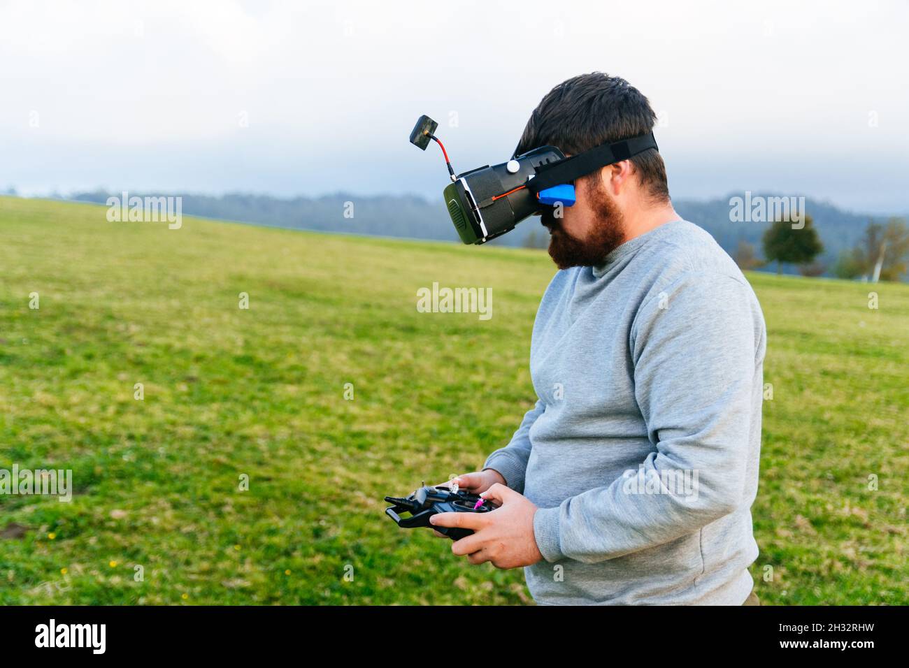 Bearded man using a drone with remote controller wearing virtual reality glasses making photos and videos . Young guy having fun with new vr technolog Stock Photo