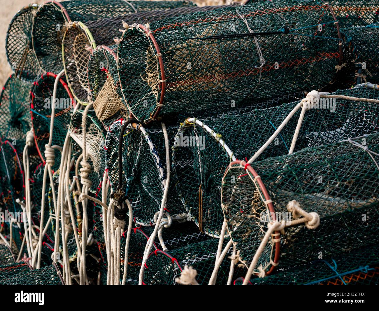 fishing equipment, cylindrical fishing net traps with ropes on a pier Stock Photo