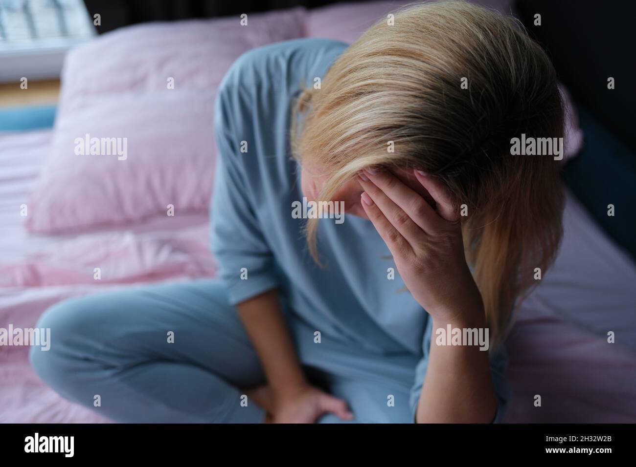 Tired Pyjamas Tired woman in pajamas sitting on the bed, close-up Stock Photo - Alamy