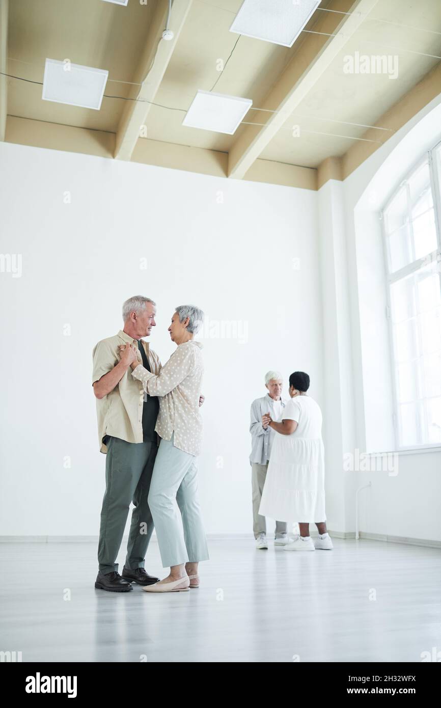 Two elderly couples enjoying dance with each other during lesson in dance studio Stock Photo