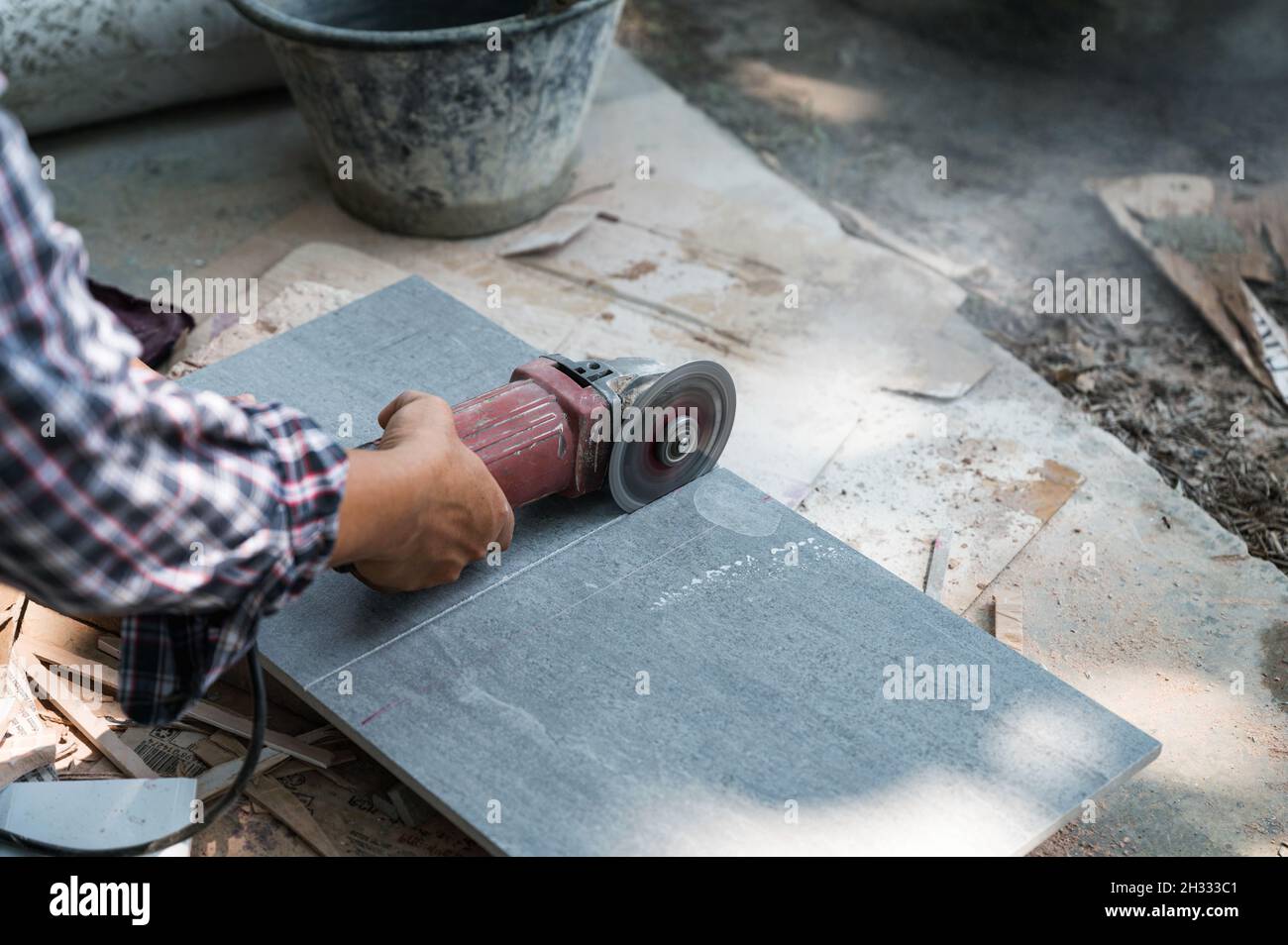 Worker using electric circular saw cutting granite tile in construction site Stock Photo