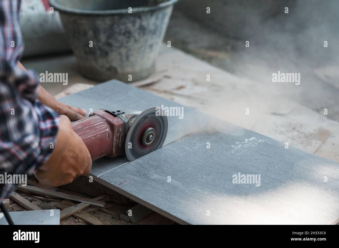 Worker using electric circular saw cutting granite tile in construction site Stock Photo