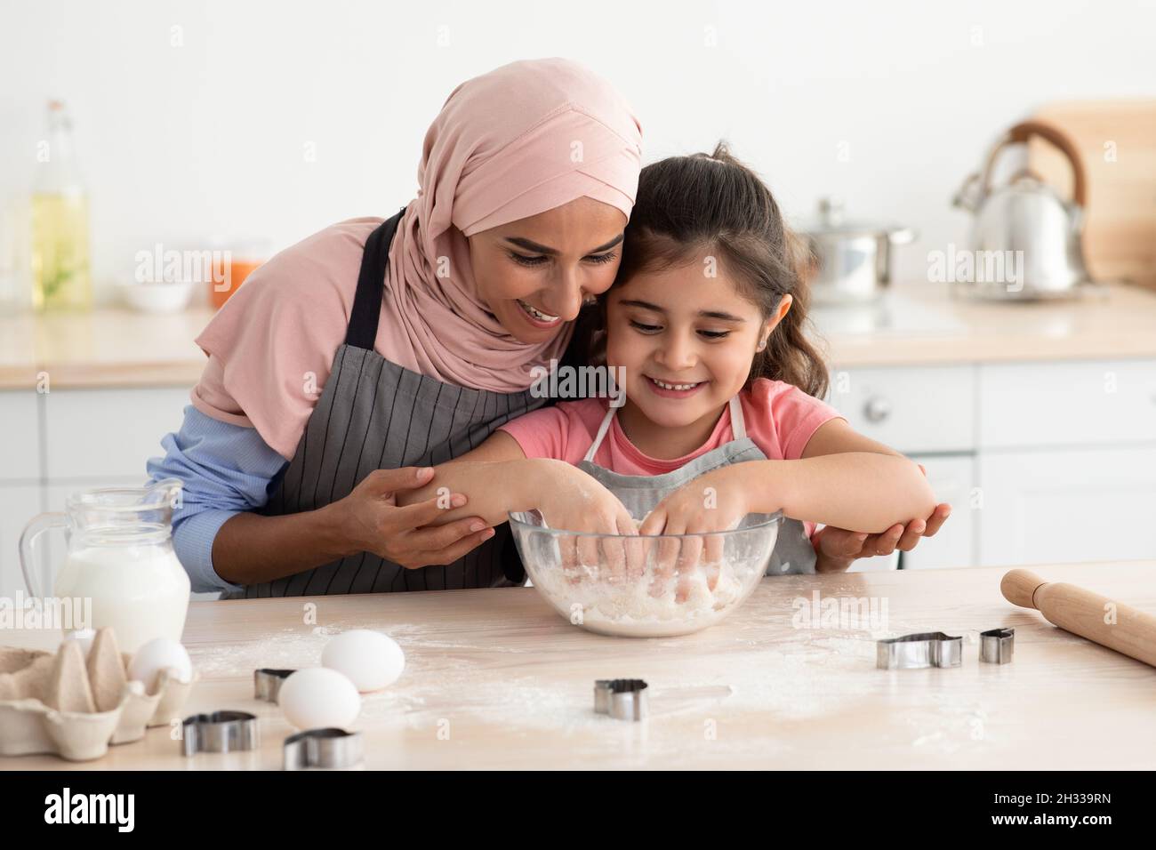 Cute Little Girl Baking In Kitchen With Her Muslim Mom, Happy Islamic Lady In Hijab Teaching