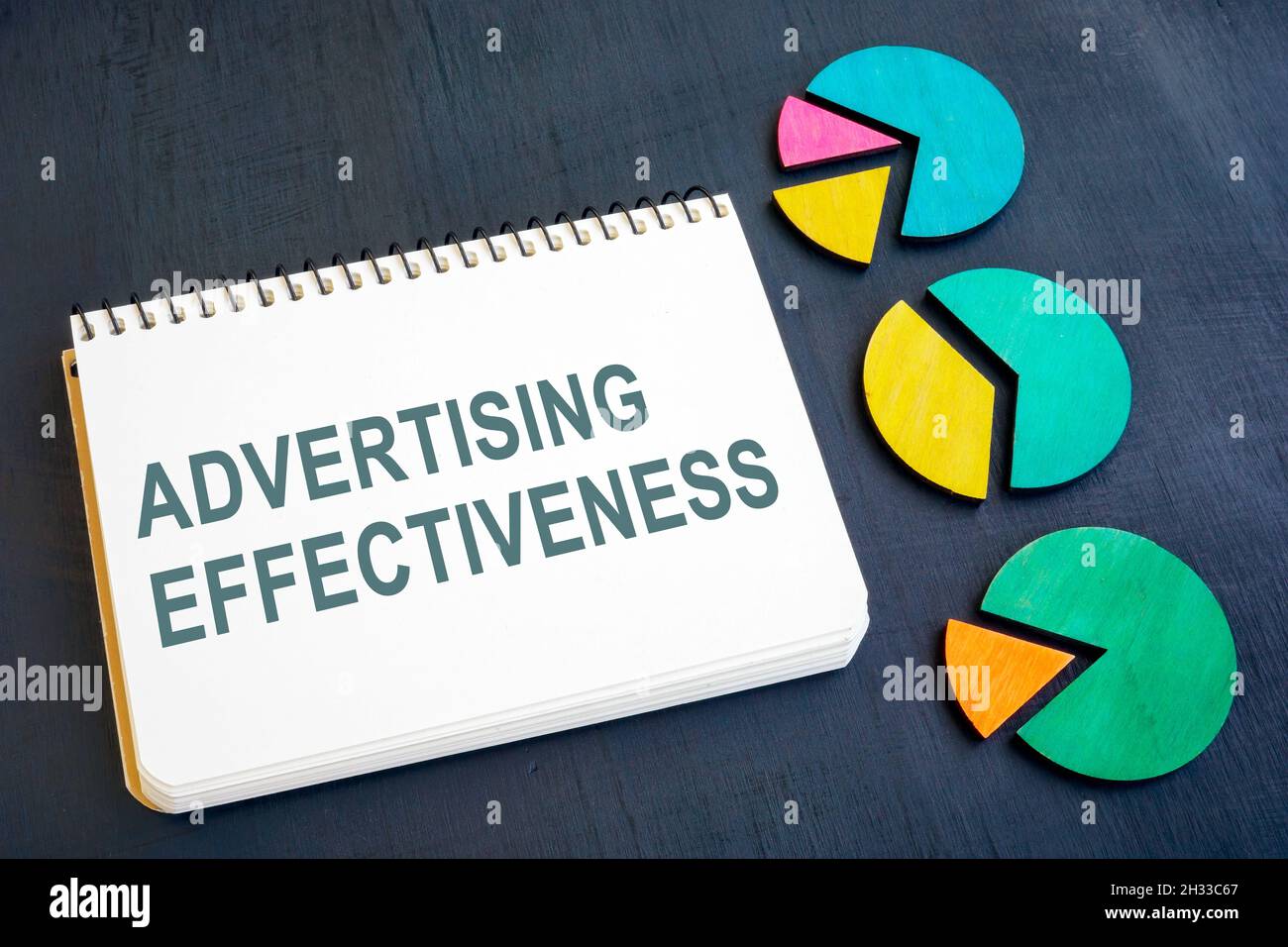 Advertising effectiveness concept. Notepad and charts on a dark surface. Stock Photo
