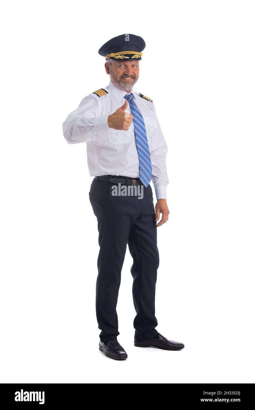 Cheerful airline pilot wearing uniform with epaulets showing thumb up gesture of approval, standing isolated on white background. Stock Photo