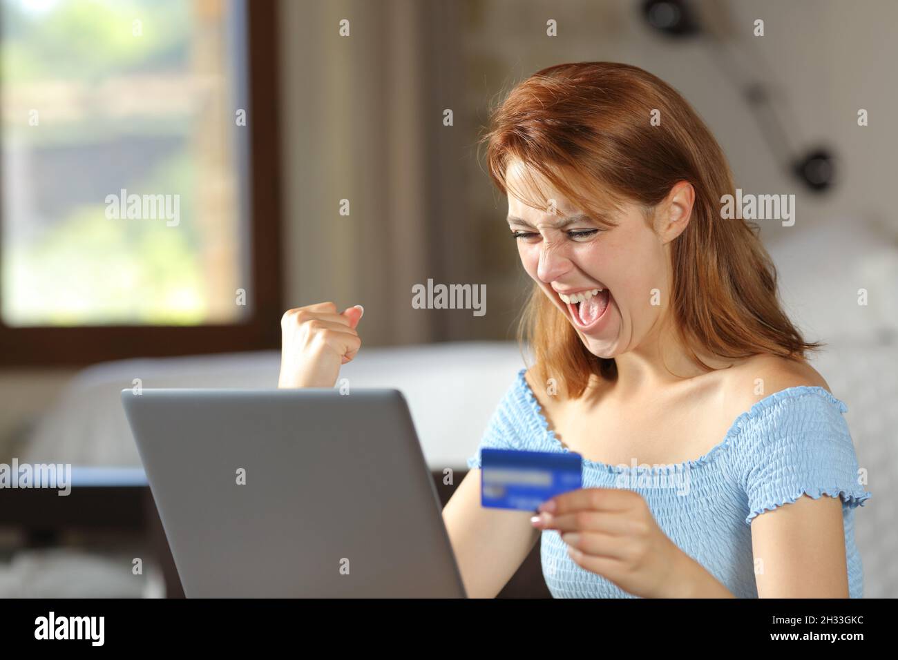 Excited woman buying online with credit card celebrating at home Stock Photo