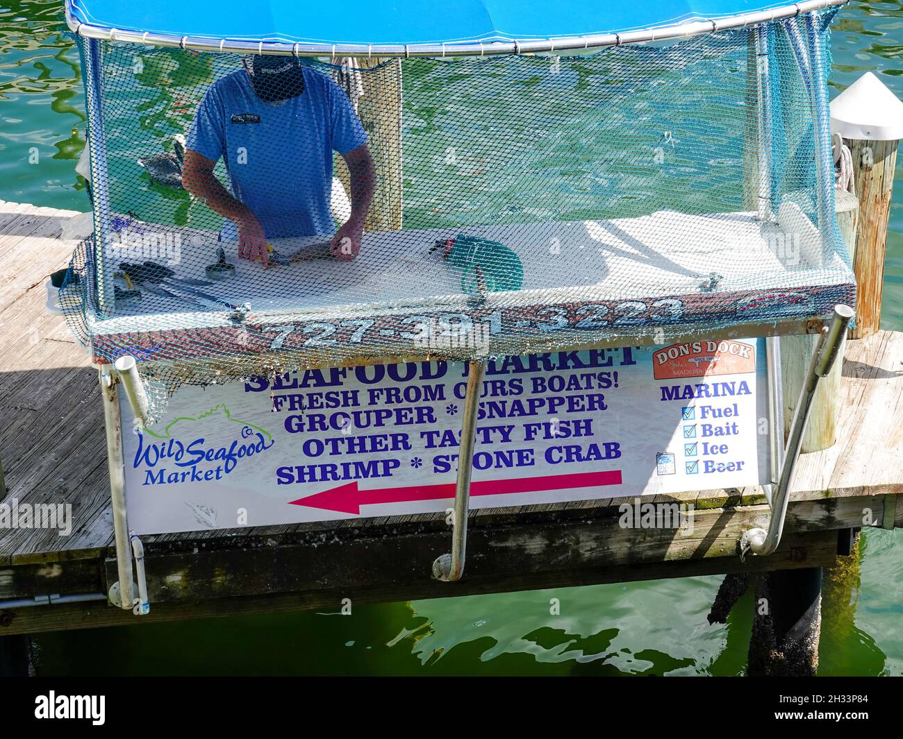 Man cleaning fish at dock kiosk, Wild Seafood Market, Don’s Dock at