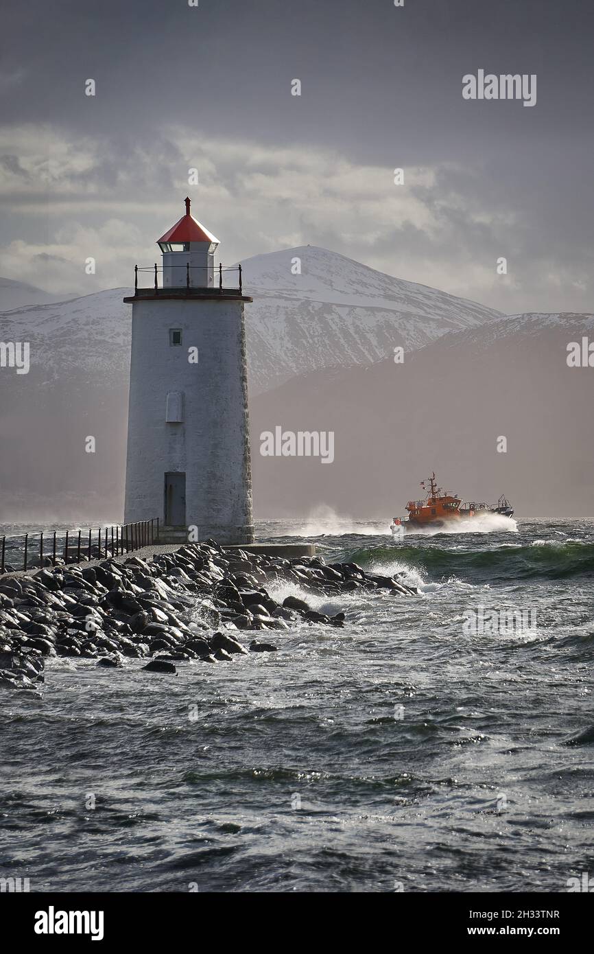 A rescue boat rushing by Høgstein lighthouse on Godøy during a storm