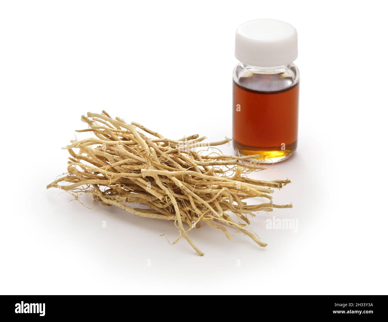 dried vetiver roots and vetiver essential oil in a glass vial, fragrance material Stock Photo