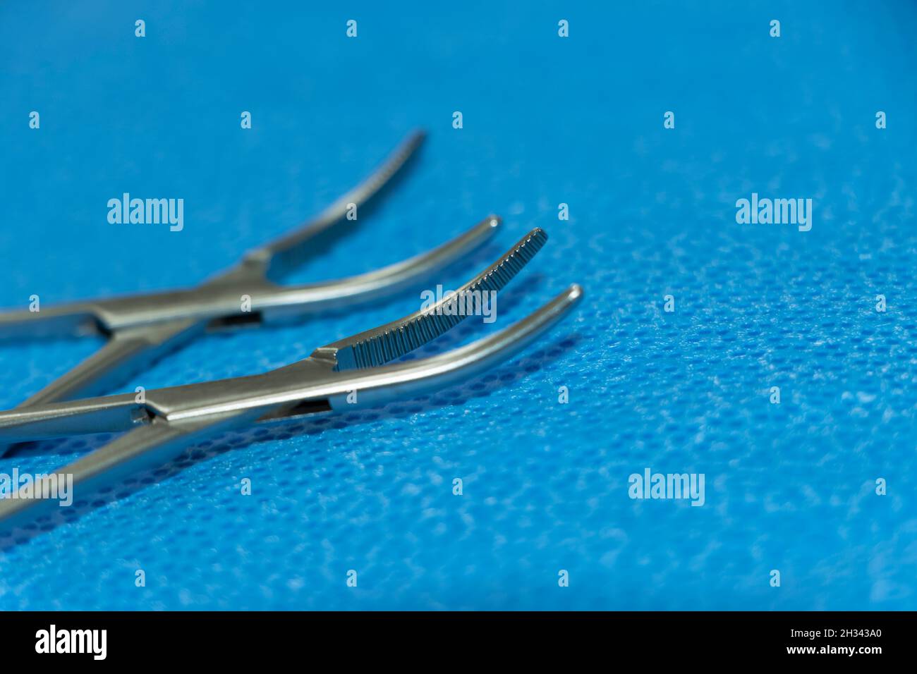 Closeup Image Of Hemostats Artery Forceps Tip In Blue Background. Selective Focus Stock Photo