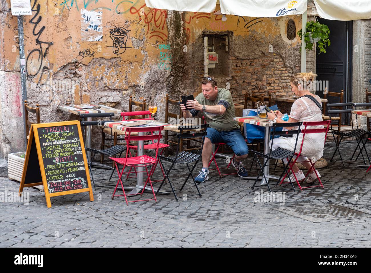 Middle-aged male tourist taking a picture of Aperol Spritz drink 