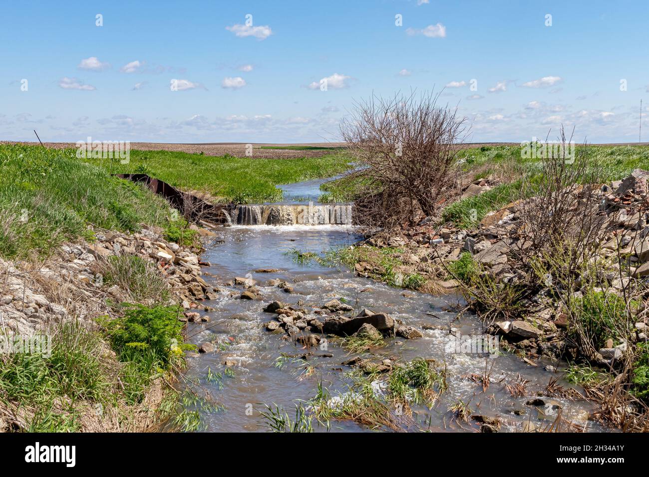 Water flowing through farm field in waterway. Concept of erosion control, drainage and water