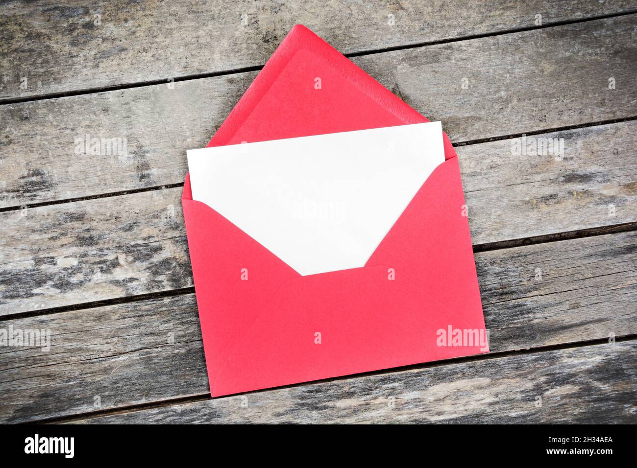 Blank white paper is placed on the open red paper envelope. Top view Stock Photo
