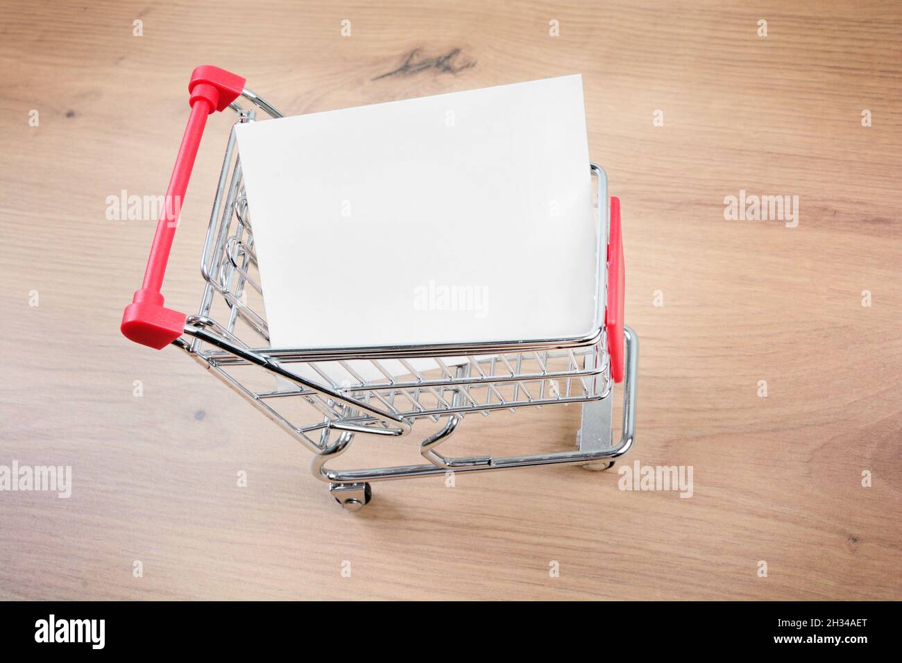 Shopping cart with empty paper on a wood table Stock Photo