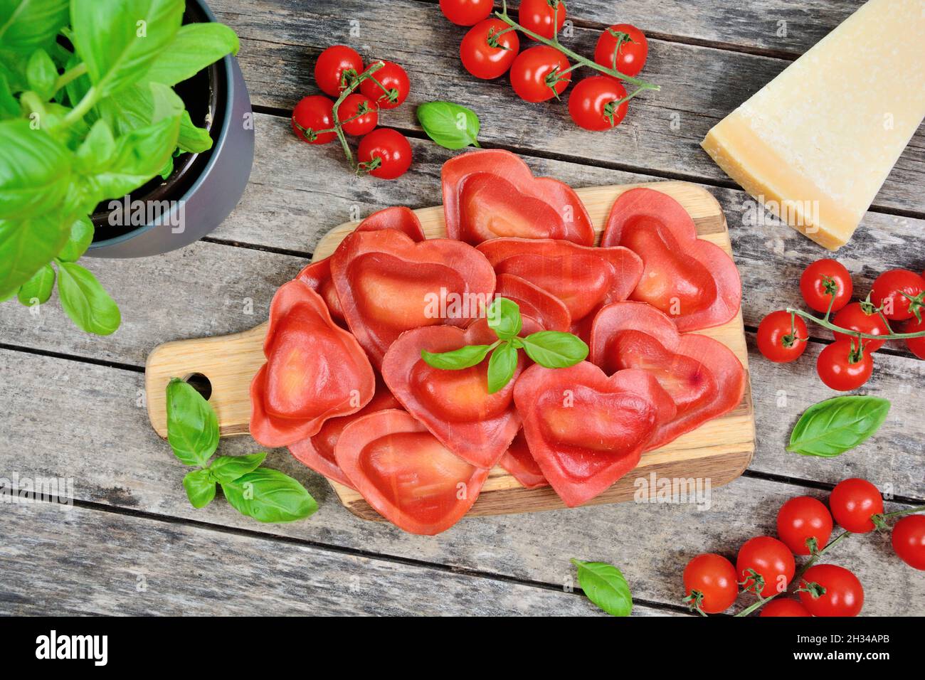 Red heart ravioli with basil and parmesan on table Stock Photo