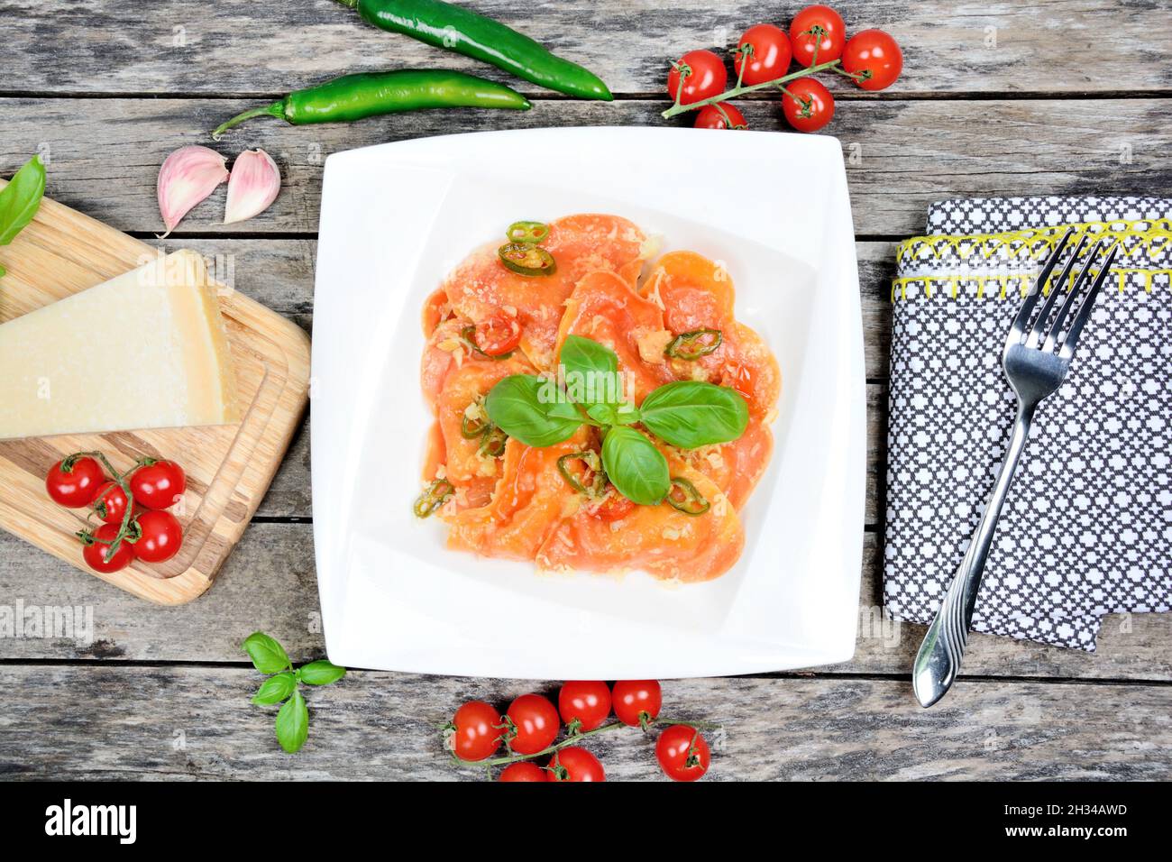 Red heart ravioli in a plate with parmesan and basil on table Stock Photo